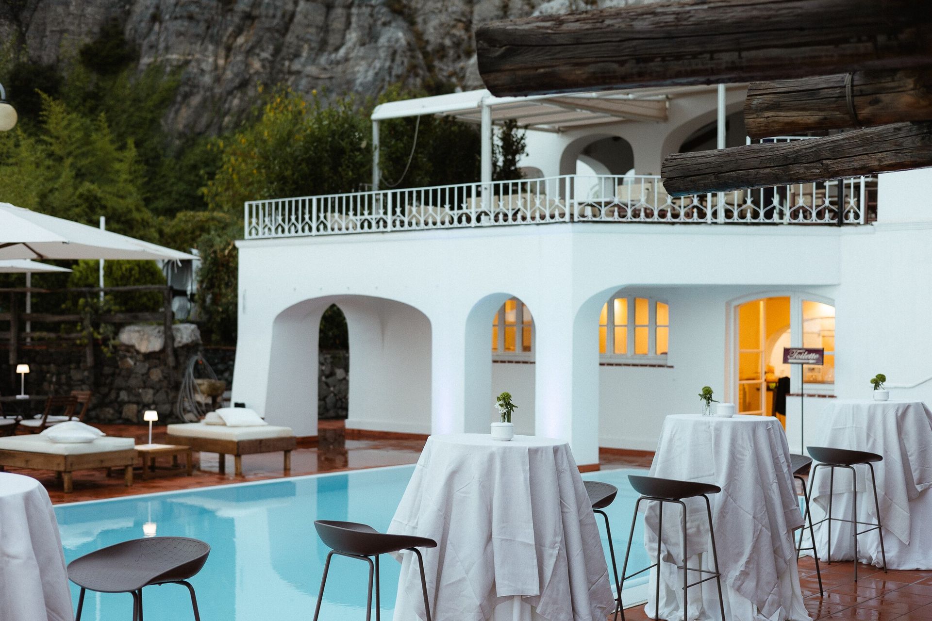 Bar all'aperto a bordo piscina con archi bianchi e scogliera